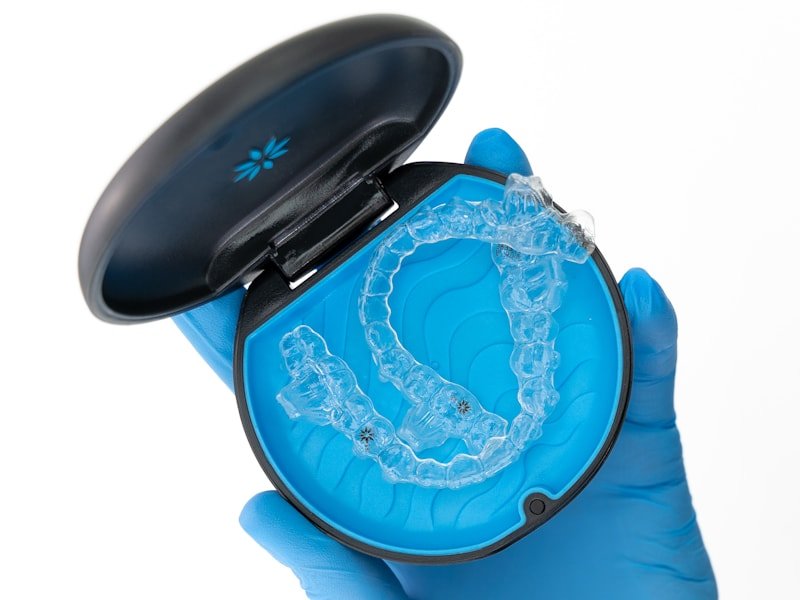 Gloved hand holding a clear orthodontic aligner in its case